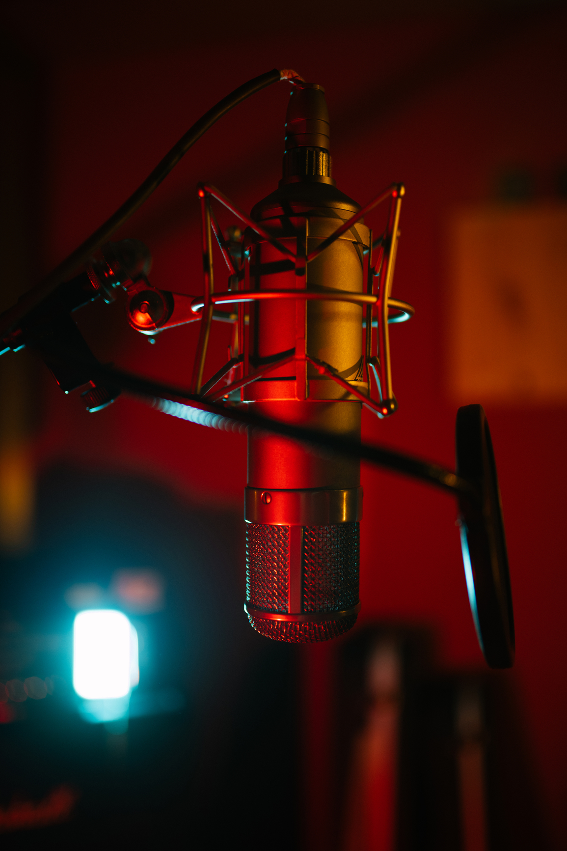 Professional mic with pop filter in modern sound studio with shiny spotlight on blurred background